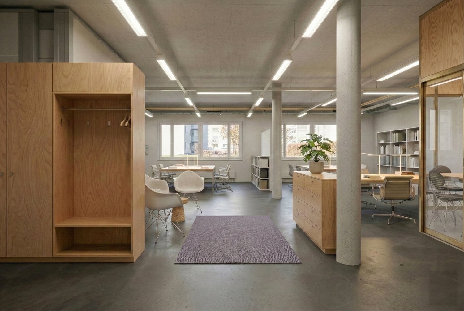 Office with modern furniture, wooden storage units, large windows, large rug, and office desks.