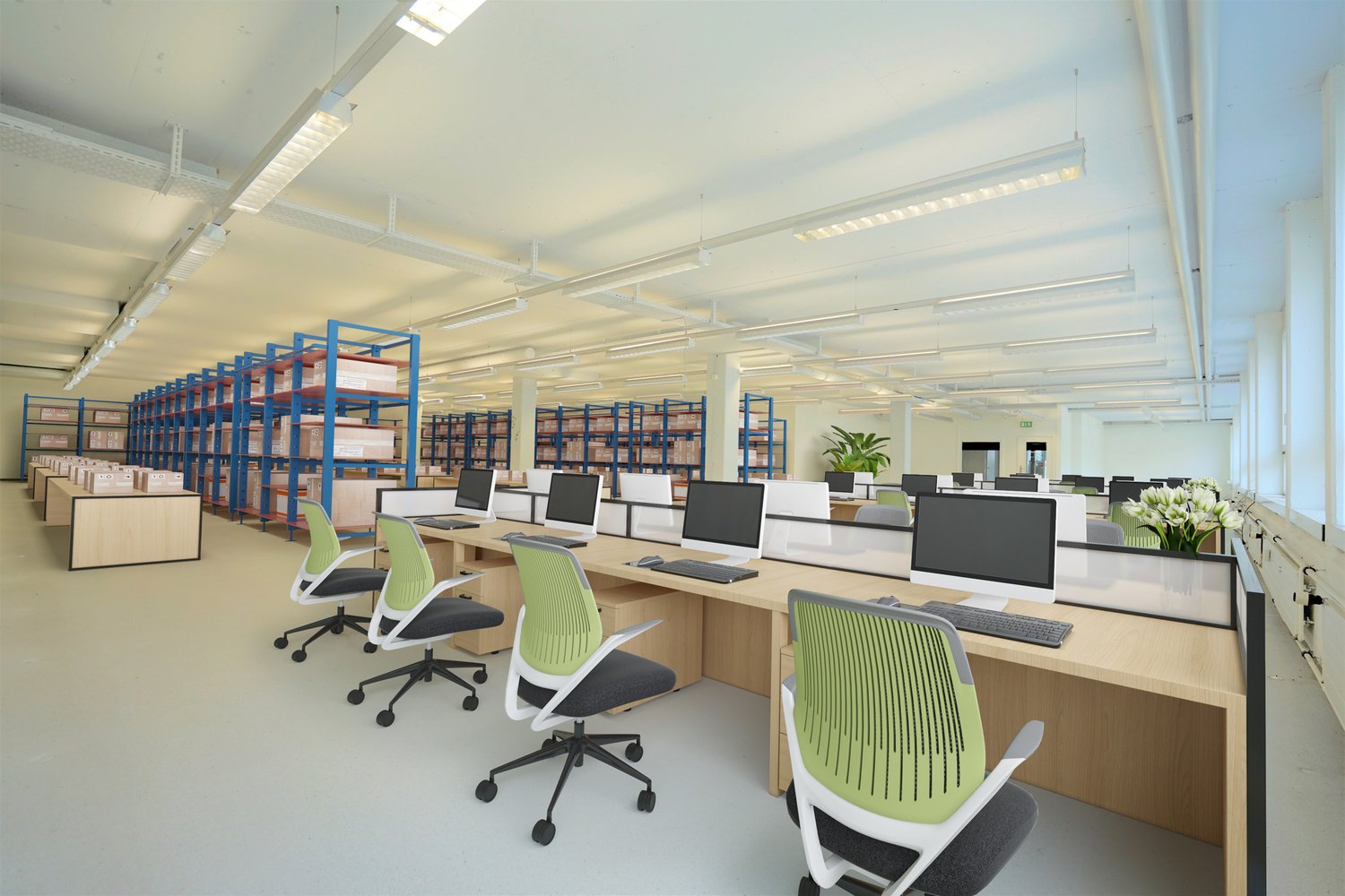 Modern office space with rows of ergonomic chairs, wooden desks, multiple monitors, keyboard and mouse, blue storage racks with boxes, artificial plants and ceiling lights.