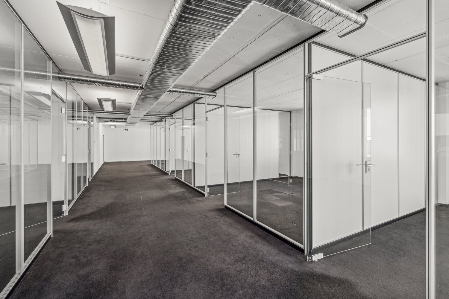 Glass walls and floor, carpeted flooring, silver pipes on ceiling, lights