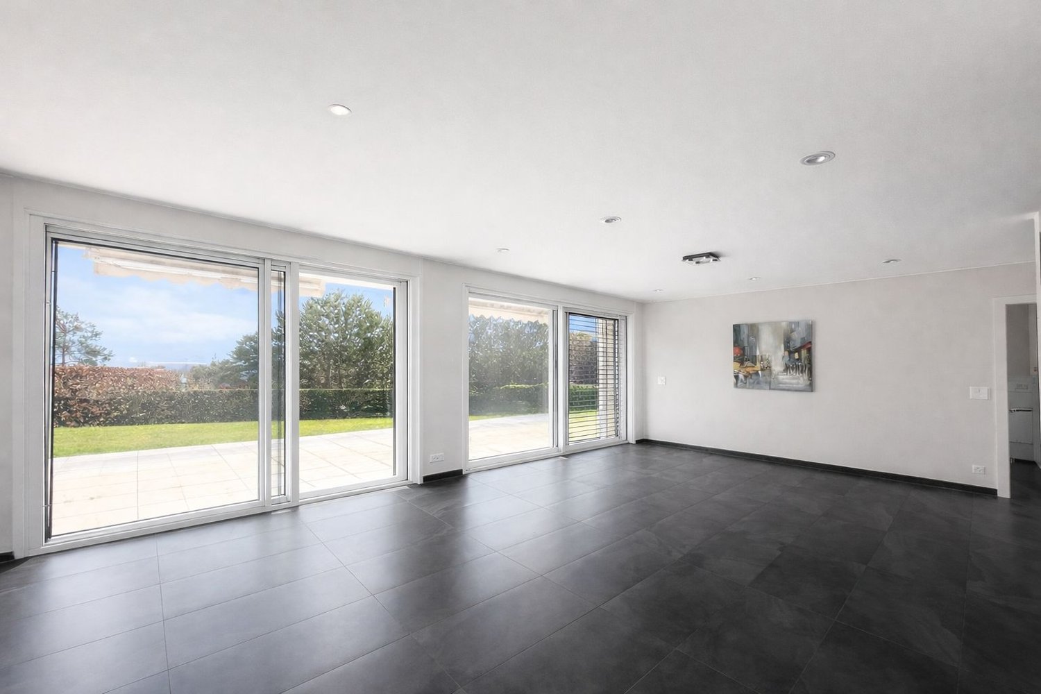 large sliding glass doors, black tiled floor, white walls, painting on wall, view of grassy area