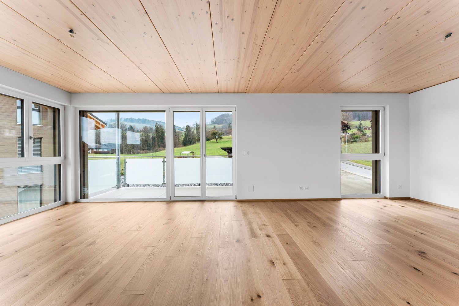 large windows, sliding glass doors, wooden floor, balcony, view of the outside
