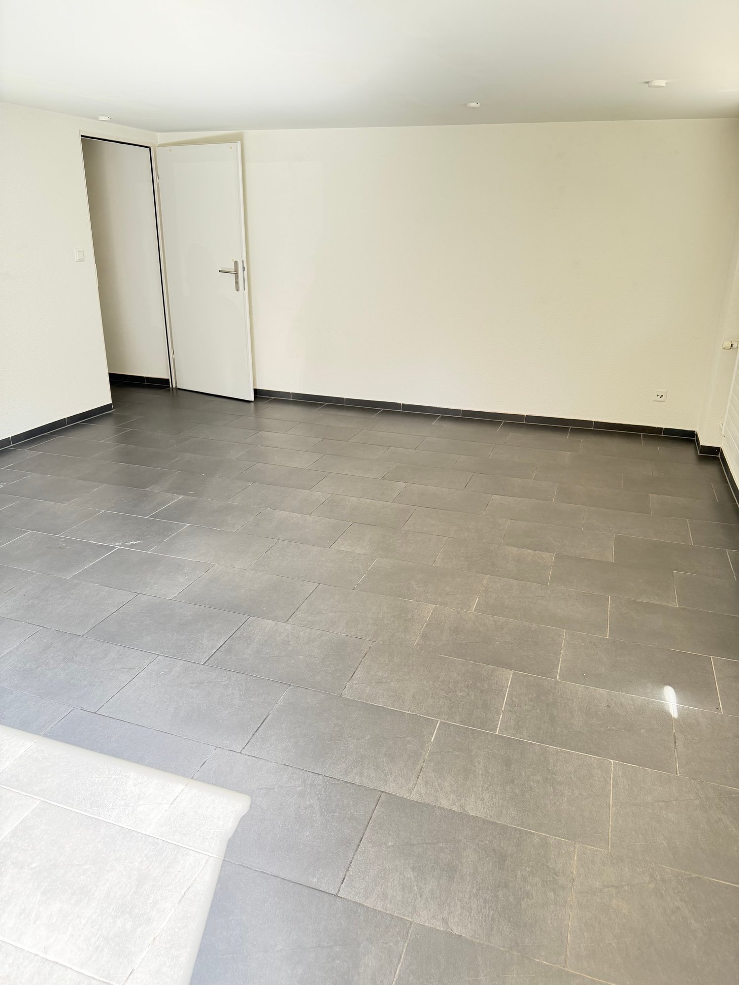 empty room, white walls, gray tiles, white doors, power outlet