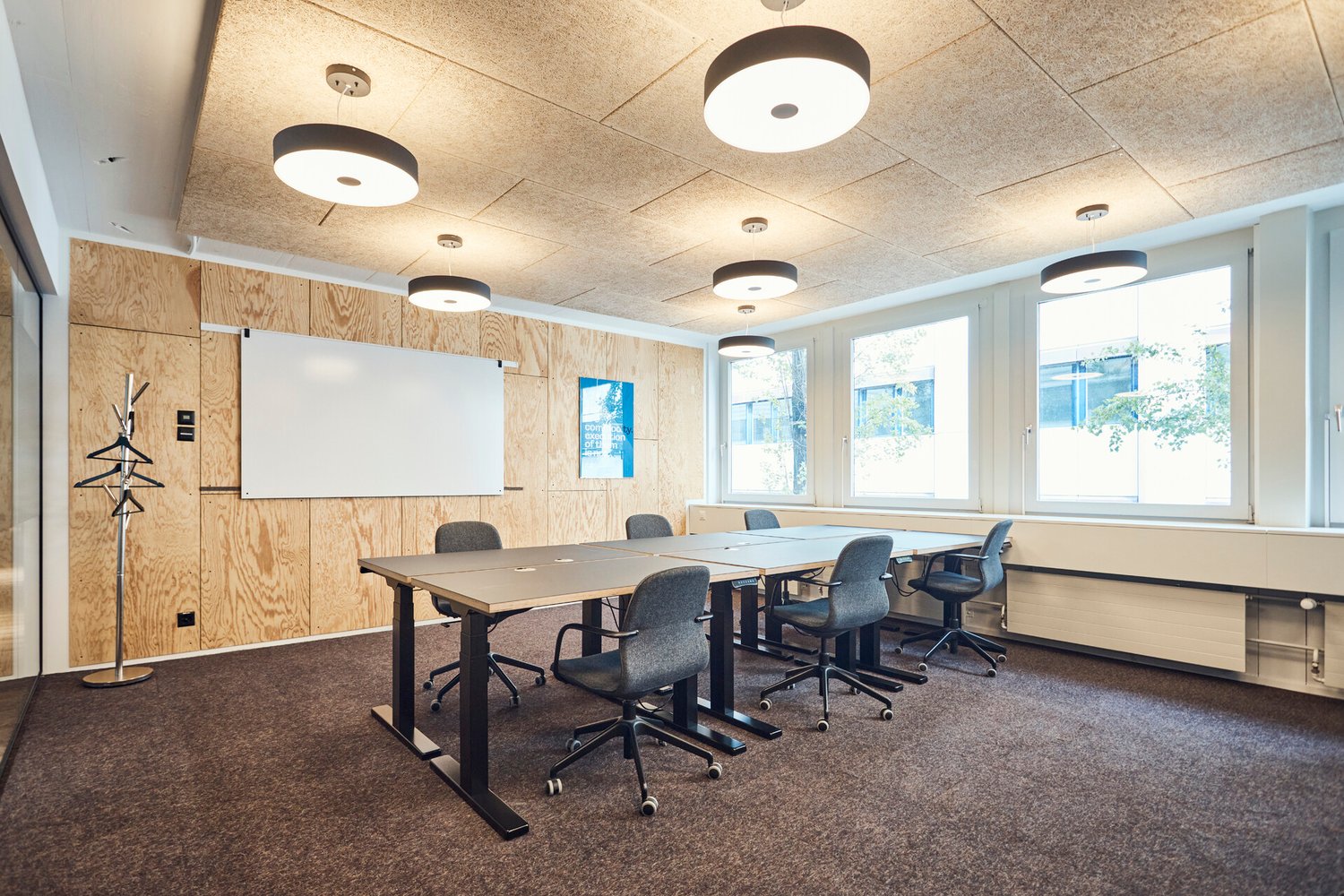 Modern empty meeting room with desks, chairs, whiteboard, and wooden paneling