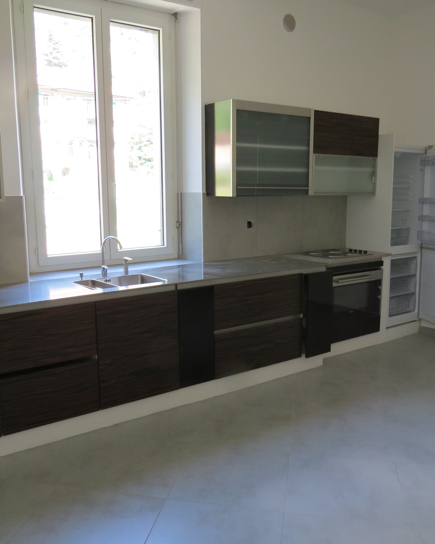 Kitchen with a sink, faucet, oven, and refrigerator under the window.