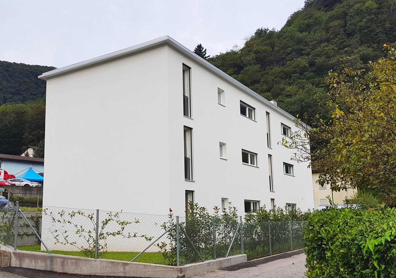 white building, several windows, fenced area, mountain in the background