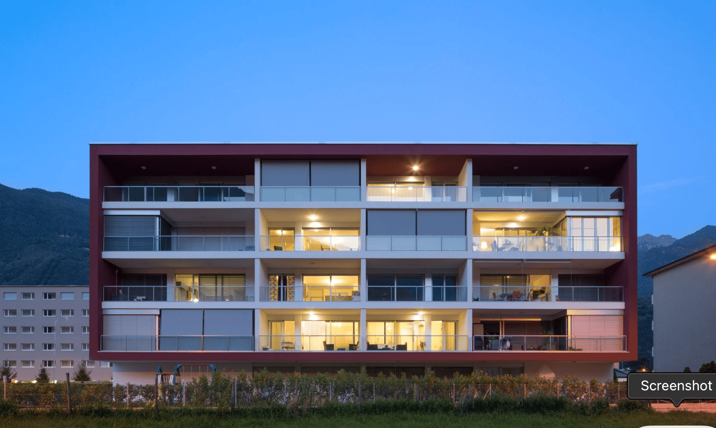 Modern multi-story residential building, multiple balconies, mountain view