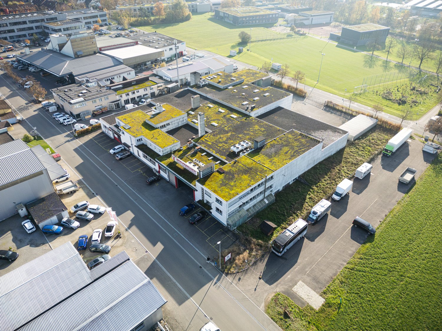 multi-storey building, green rooftop, multiple parking spots, various vehicles