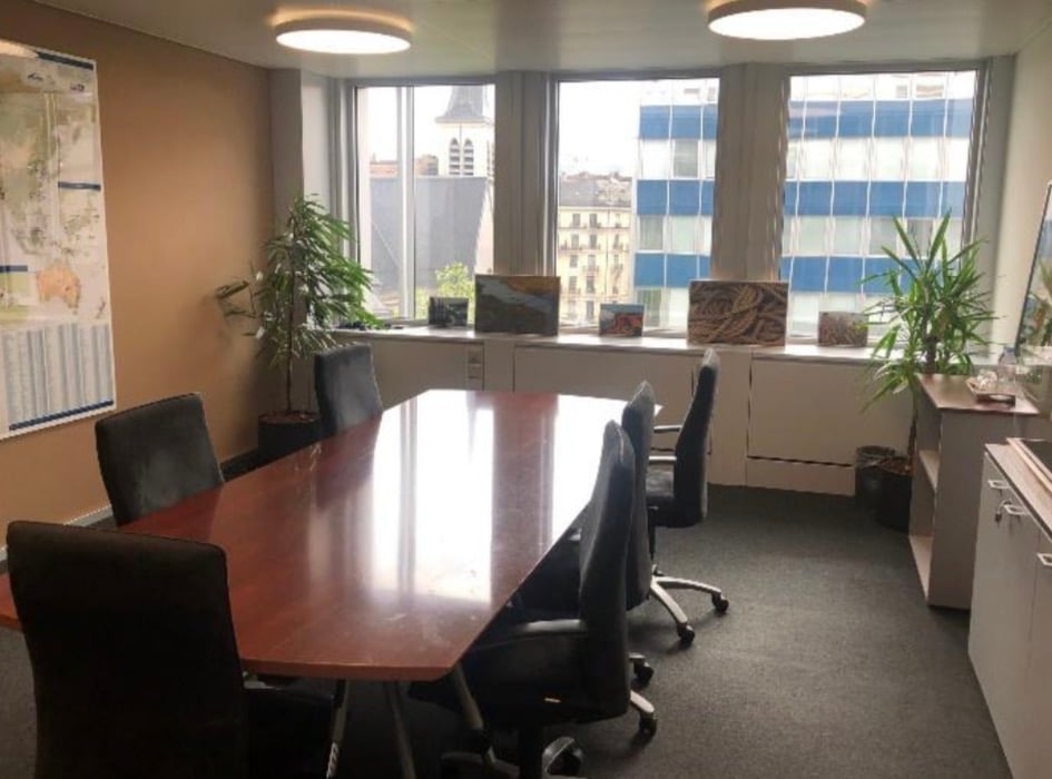 conference room with large windows, wooden table, chairs, cabinets, map on the wall, plants