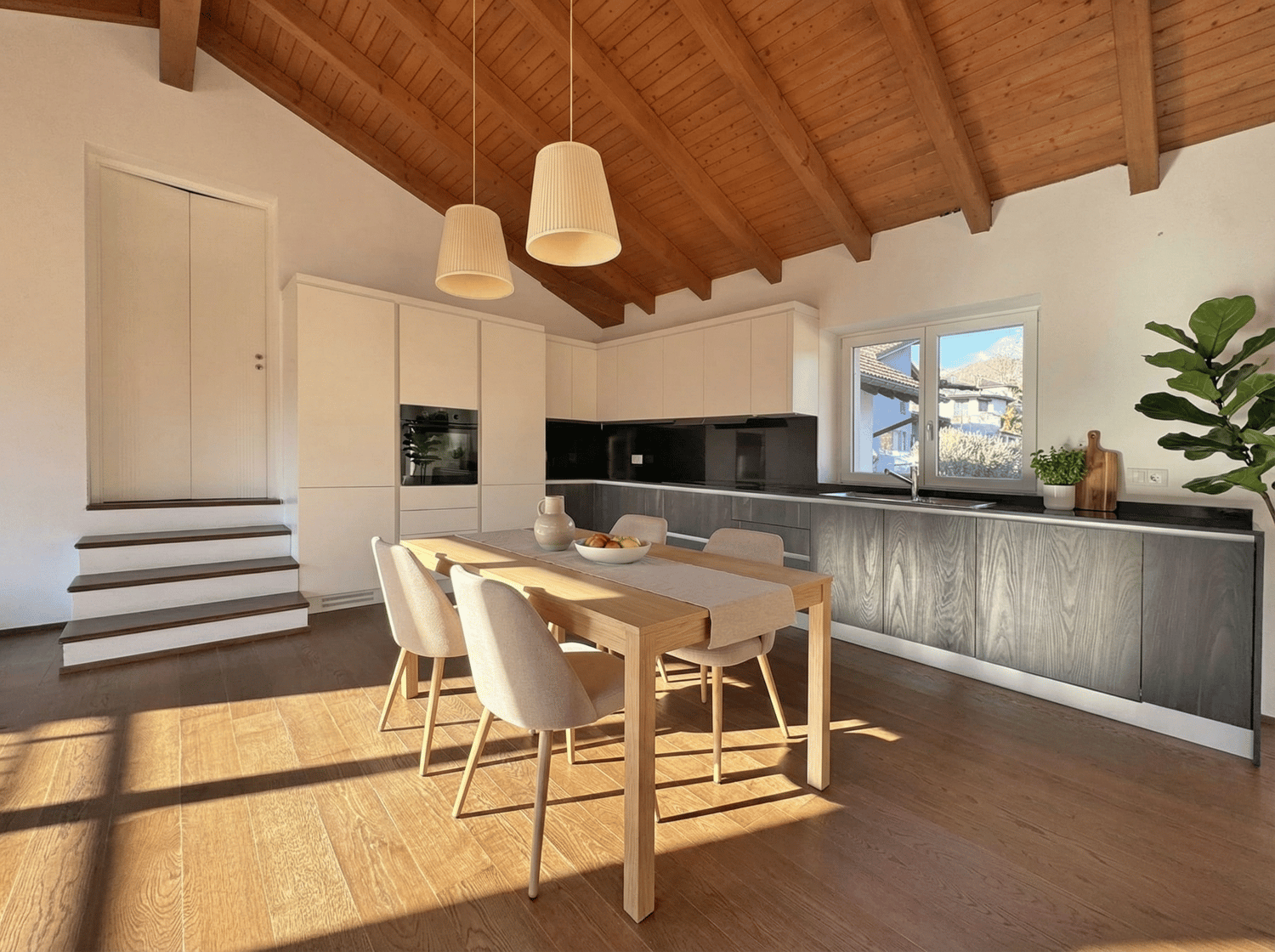Dining room with wooden table, chairs, white cabinets, wooden ceiling, white walls, kitchen with oven, sink, countertop, plants