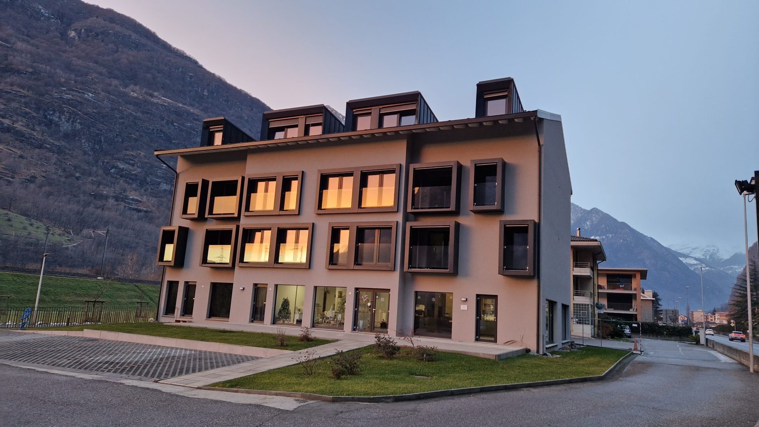 Modern apartment building, beige exterior, large windows, mountain view