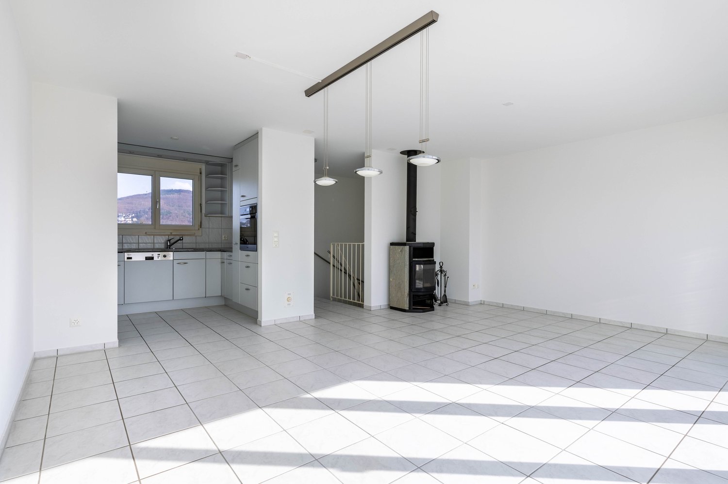 empty room, white tiles, white walls, kitchen area, fireplace, hanging lamps