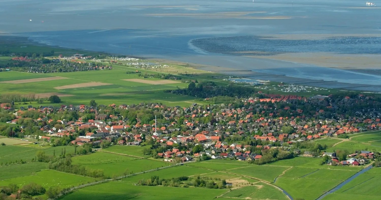Aerial view of a village with many houses, green fields, and a river