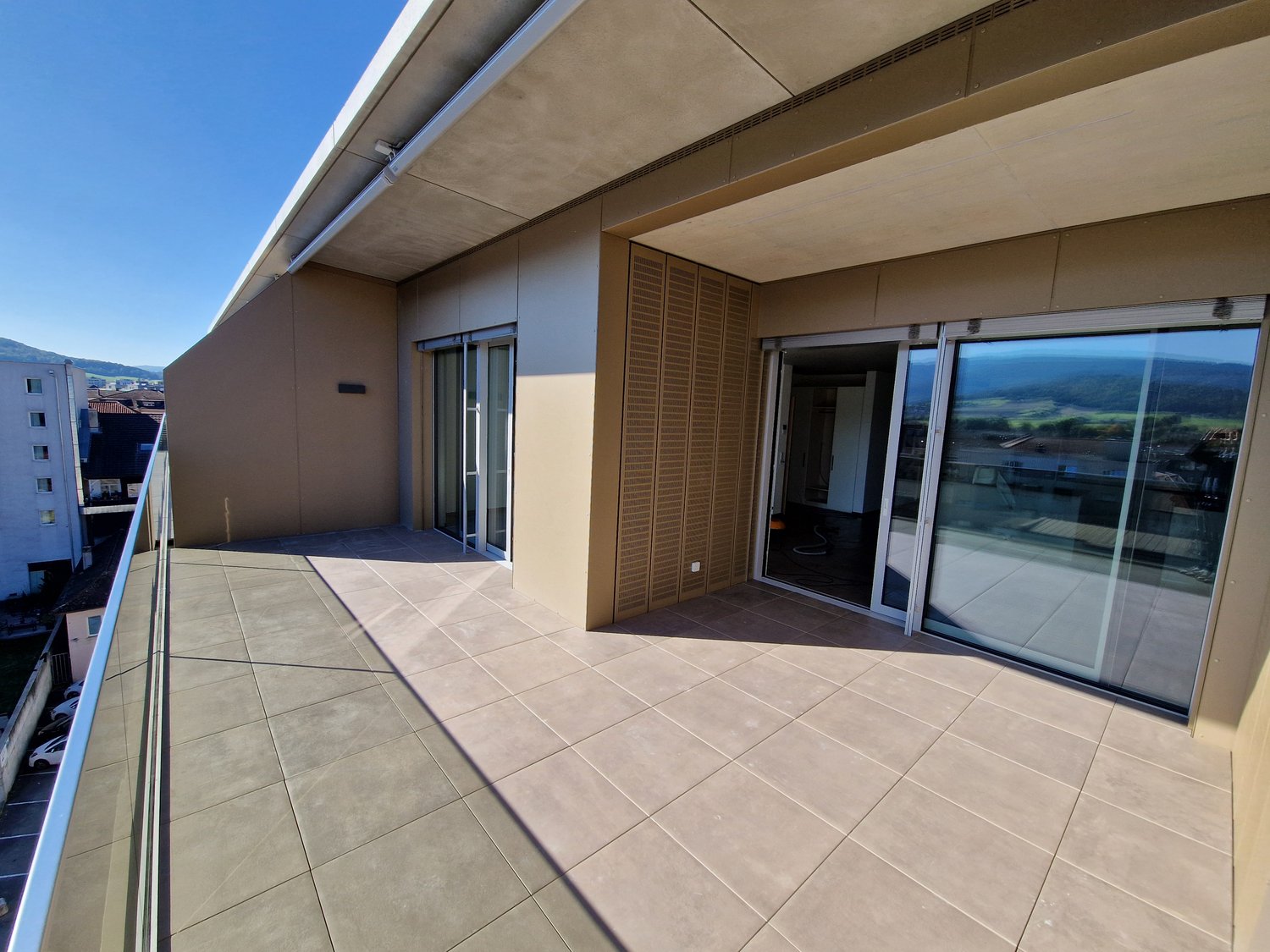 large balcony, glass doors, tiled floor, metal railing, view of the mountains