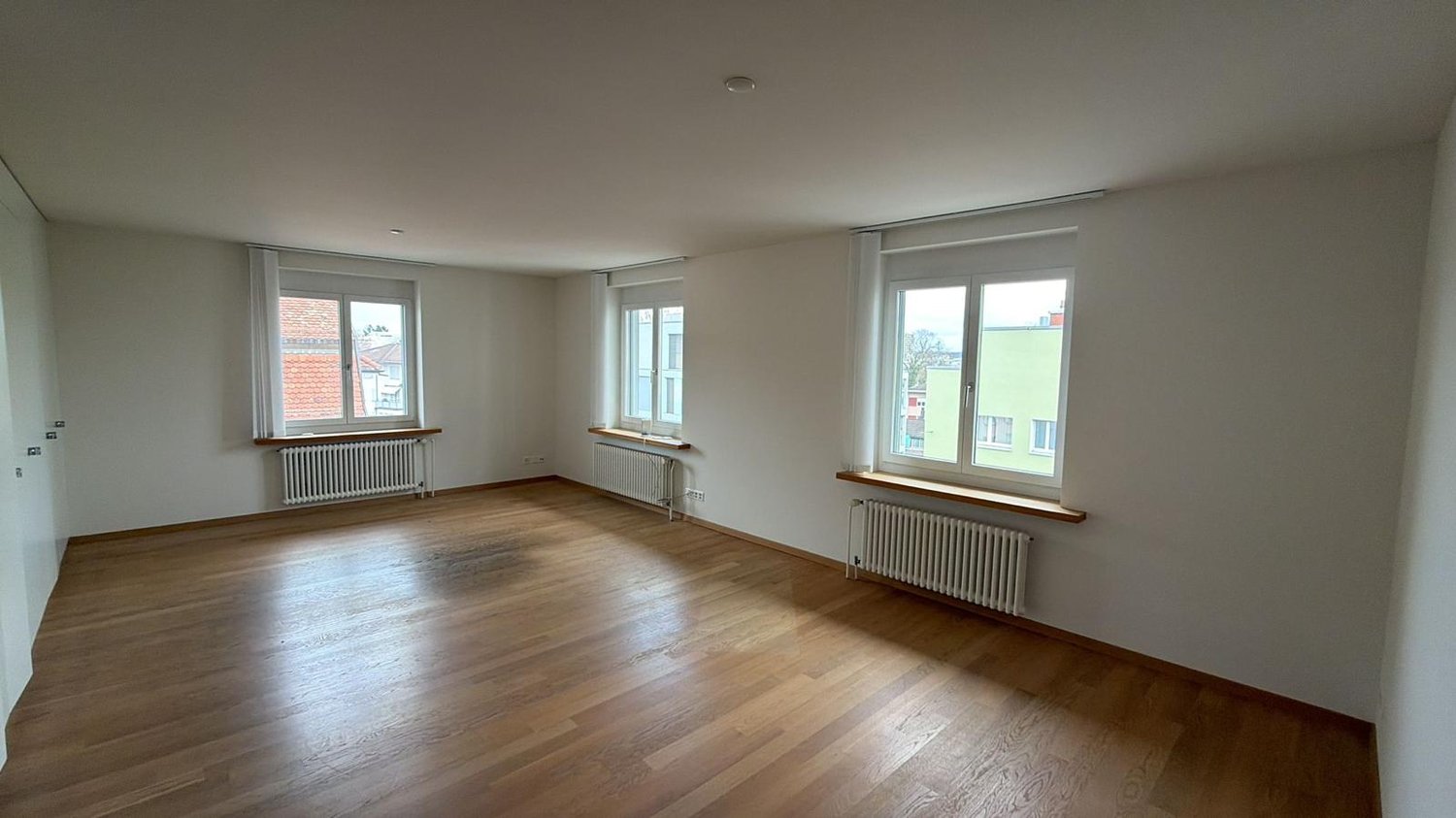 empty room, wooden floor, white walls, three windows, radiators