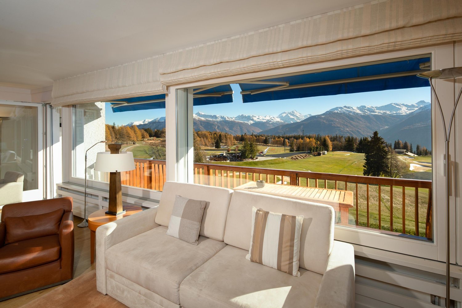 large windows, balcony, couch, lamp, brown leather armchair, wooden floor