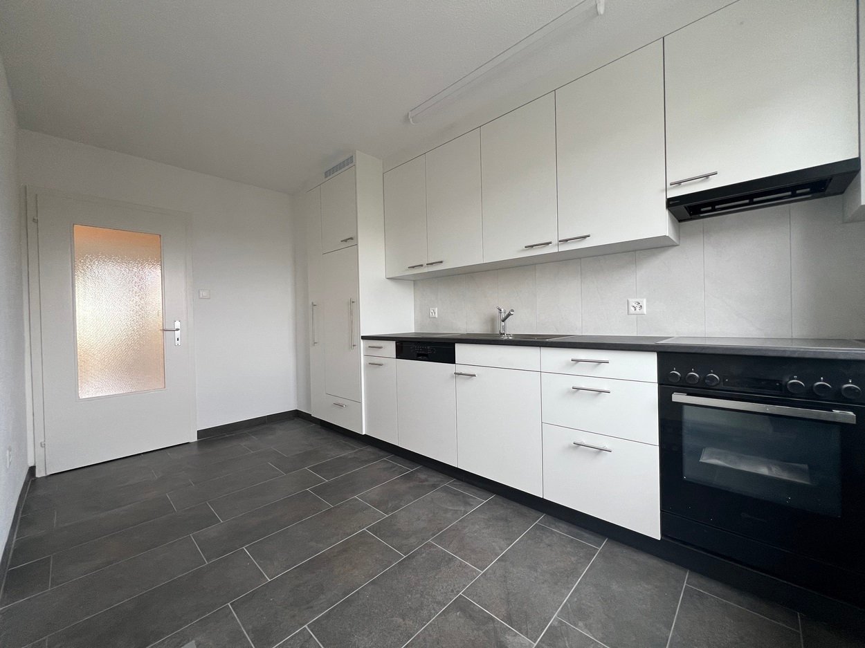 modern kitchen with white cabinets, black countertops, integrated dishwasher, washing machine, oven, sink, faucet