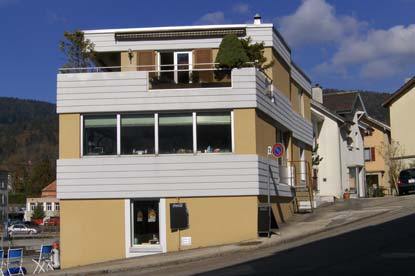 3 story building, yellow and white facade, balcony on the upper floor, street-side entrance, windows, street sign
