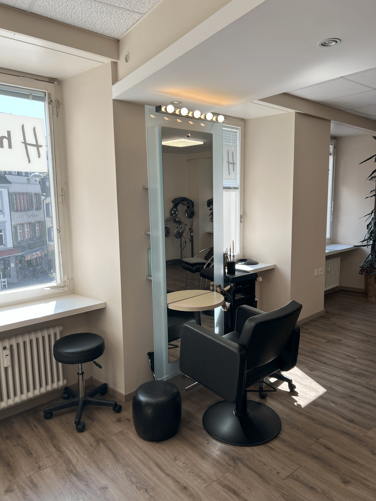 {"visible_features": [],    "type": "Room",    "description": "Hair salon with wooden floor, black rotating chair, stool, round table, mirror, radiator, ceiling light, and window",    "localized_descriptions":        {        "EN": "Hair salon with w