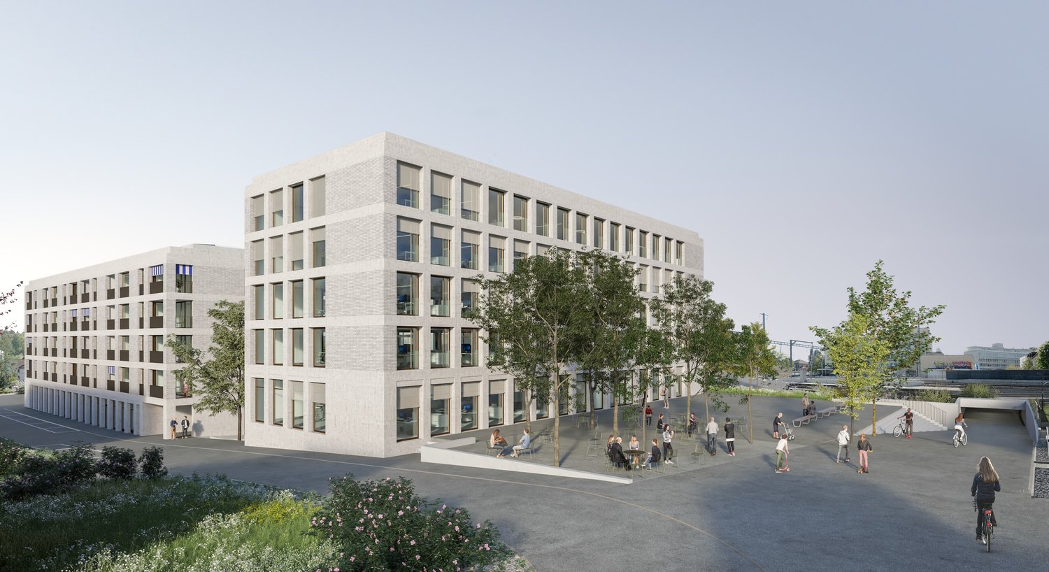 White modern building, multiple windows, raised ground floor, wide open plaza with seating, greenery