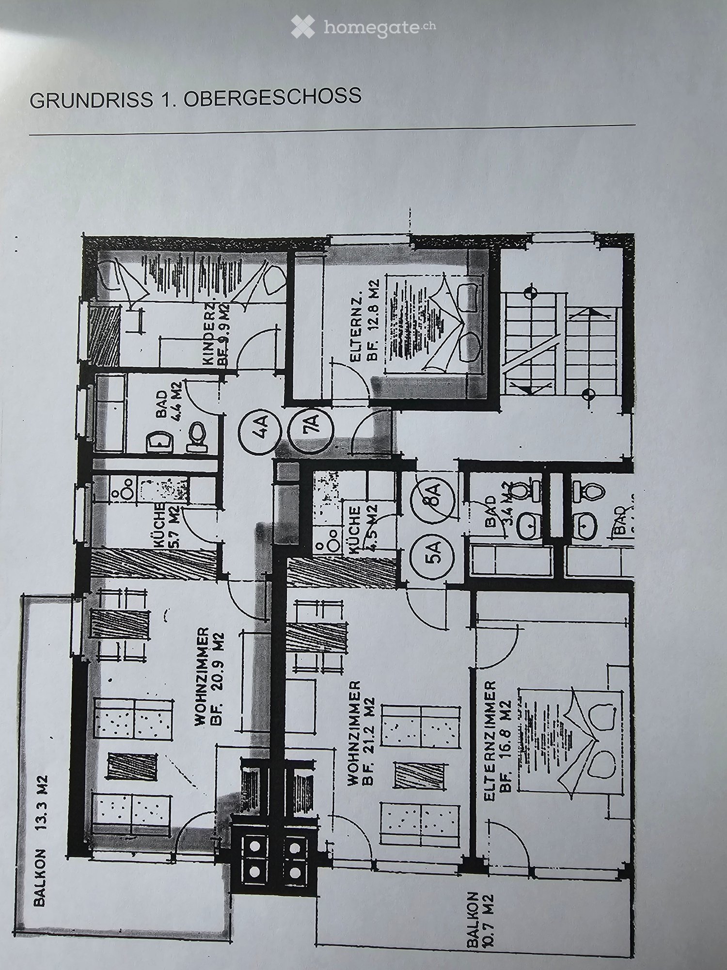 The image shows the floor plan of the first floor (Obergeschoss) of a building. It includes a living room, kitchen, 2 bedrooms, 2 bathrooms, and a balcony.