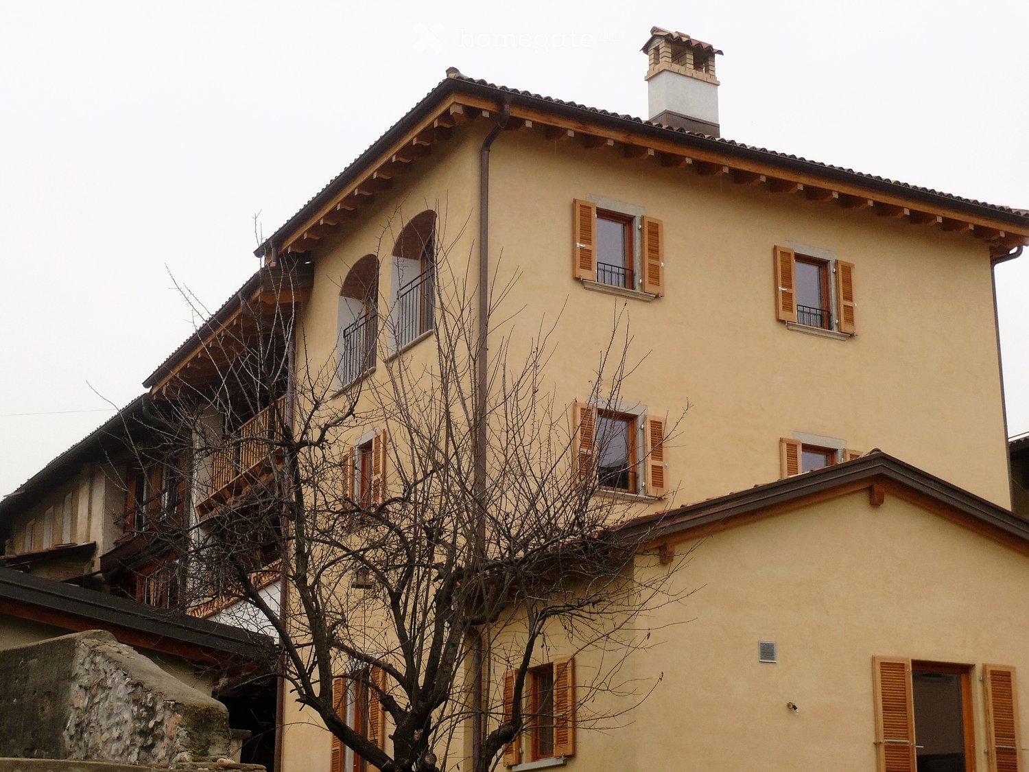 Multistory building, light beige color, arched windows, wooden balcony, chimney, multiple balconies