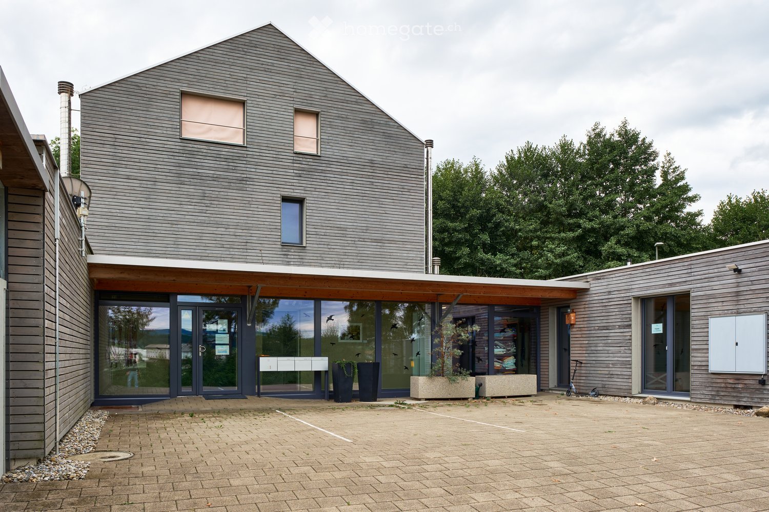 contemporary design, brick exterior, glass windows, entrance with sliding doors, two buildings, parking lot