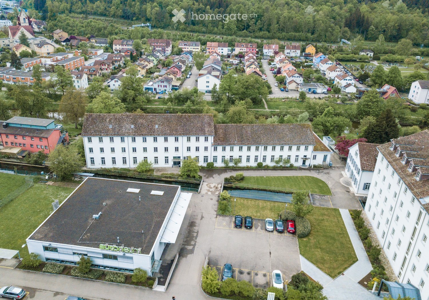 two storey house, white exterior, several windows, large parking area