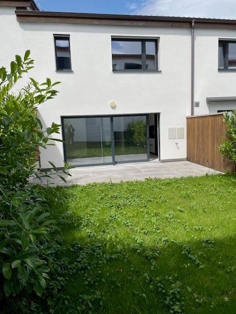 modern white house, large glass sliding doors, wooden fence, green lawn