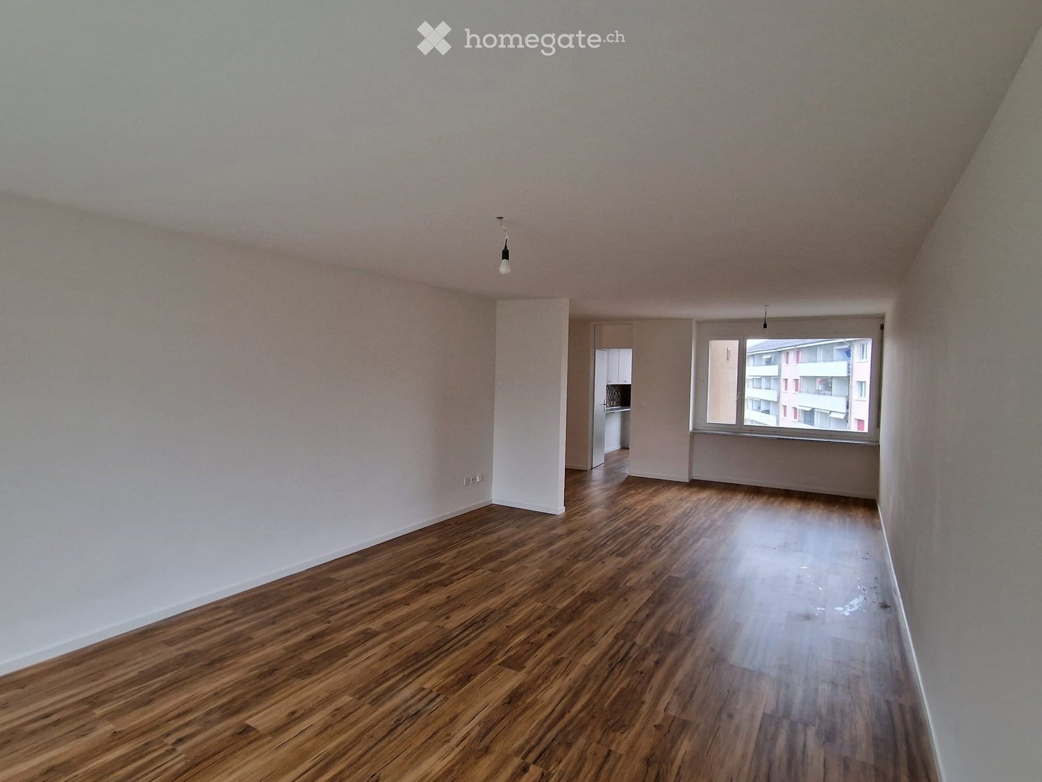 empty room, hardwood floor, white walls, window with white frames, lamps hanging from ceiling