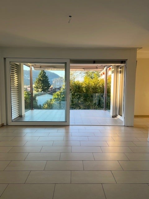 Open terrace with floor to ceiling windows, panoramic view of a mountain and lake