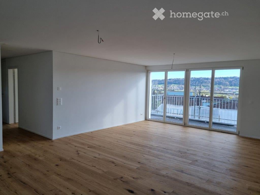 large empty room, sliding glass doors leading to balcony, wooden floor, white walls, power outlets, no furniture
