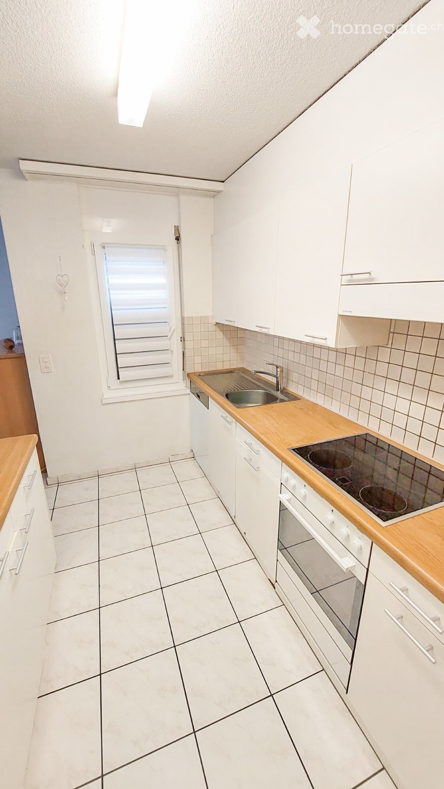 Modern kitchen with white tiles, cabinets, countertop, sink, stove, oven