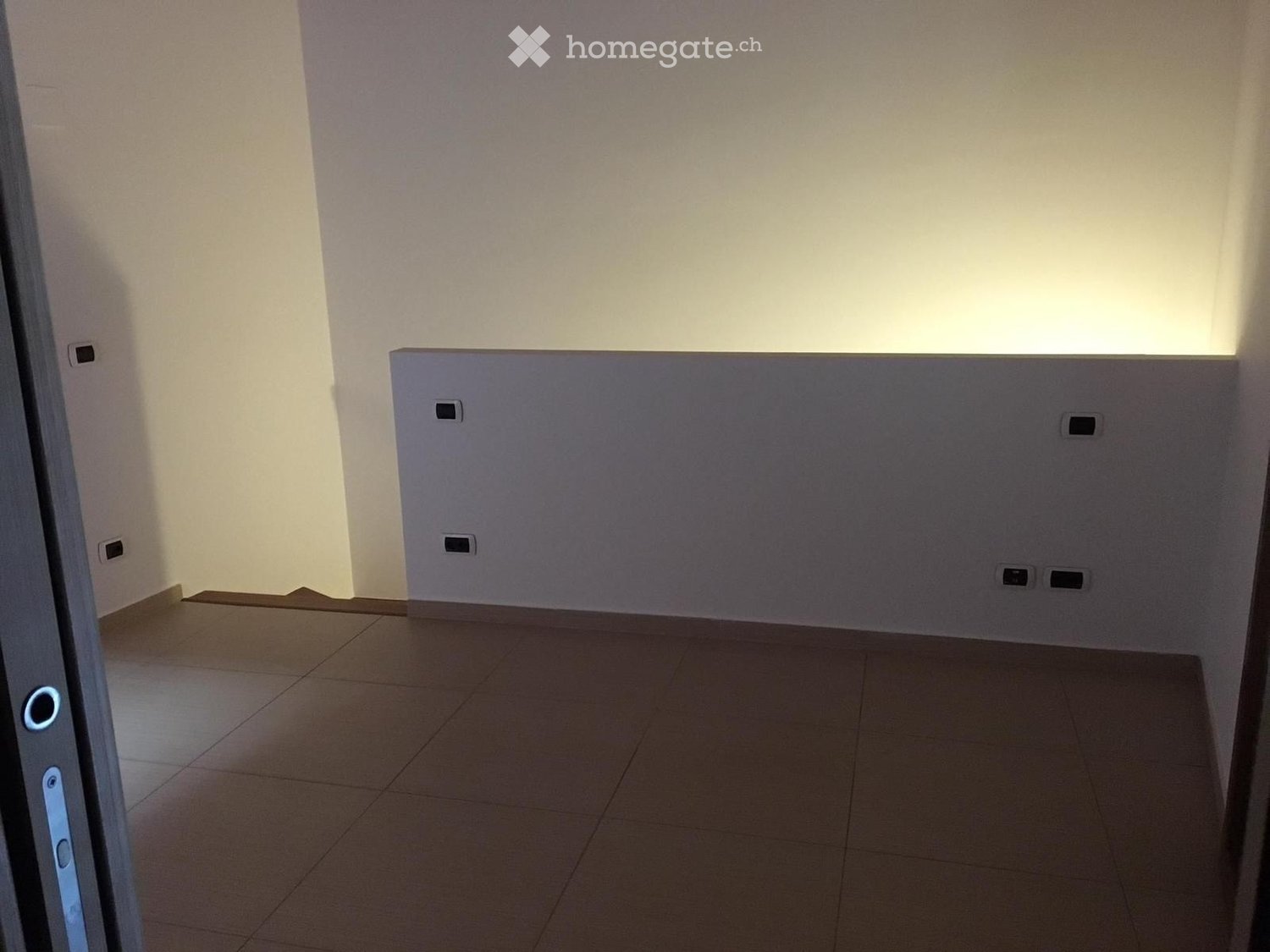 tiled floor, white walls, two power outlets, illuminated by a light