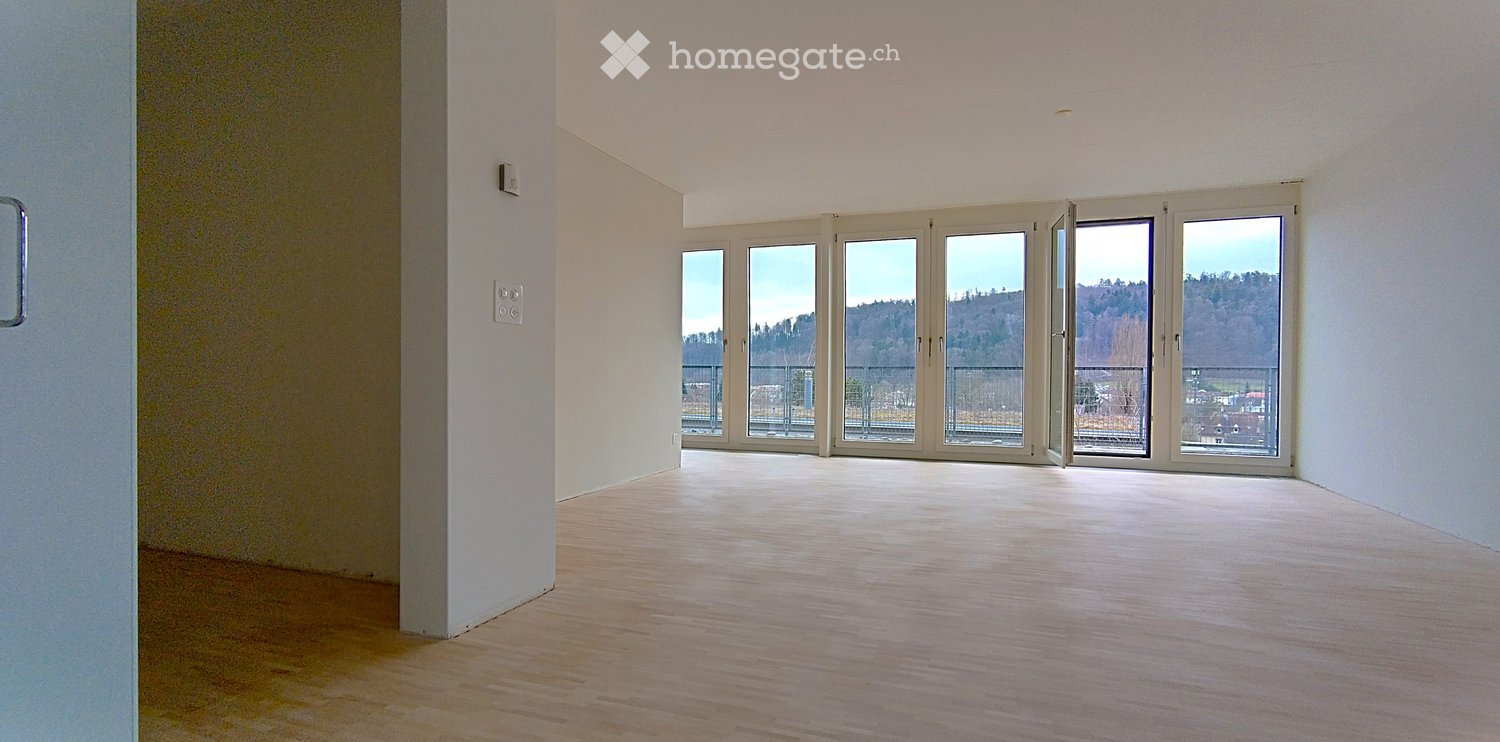 spacious room, wooden floor, white walls, large glass windows leading to balcony, no furniture