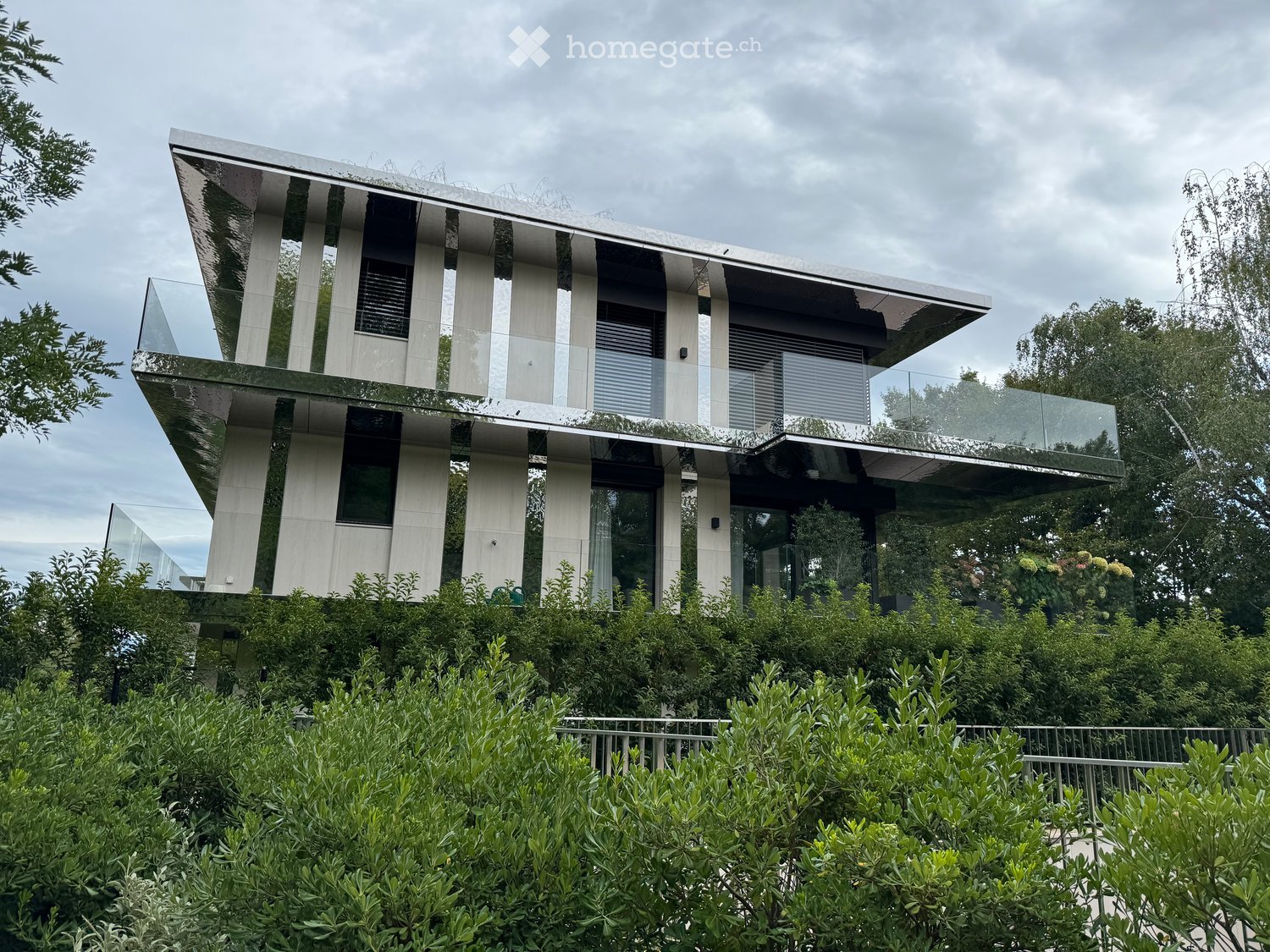 2 story modern house, reflective exterior, large glass windows, glass balconies, surrounded by greenery
