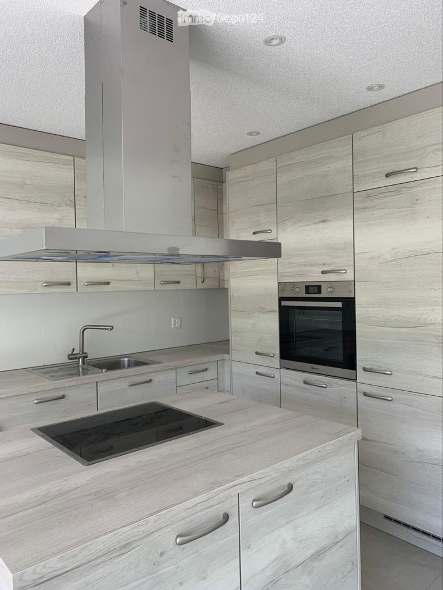 Modern kitchen with stainless steel oven, under cabinet lighting, induction stove, wooden cabinets, and large central island