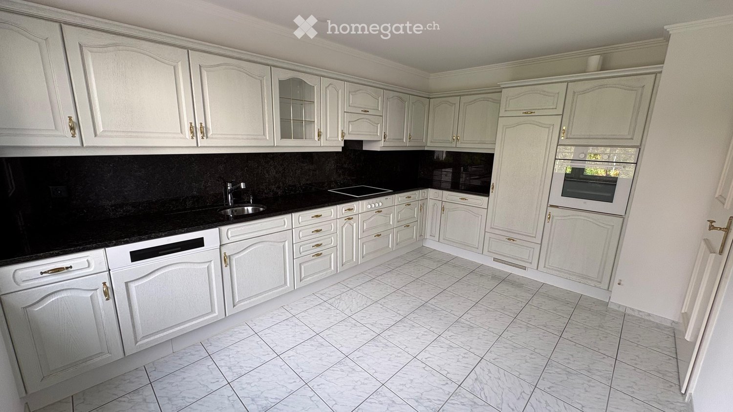 white kitchen, black countertops, white tiled floor, built-in oven, dishwasher, washing machine in cabinet