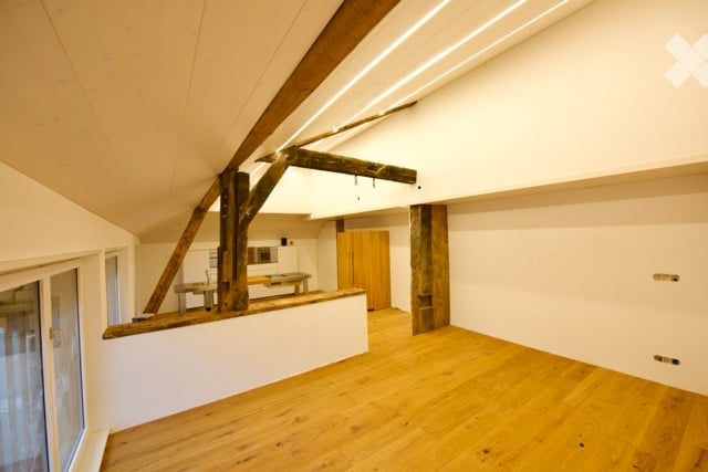 Empty attic room, wooden beams, glass windows, white walls, open balcony