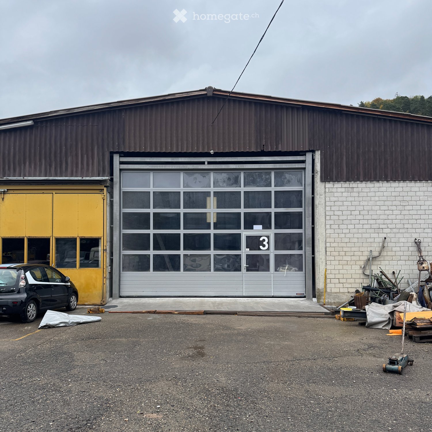 Industrial building with parking, large industrial door, yellow door, storage boxes, tools