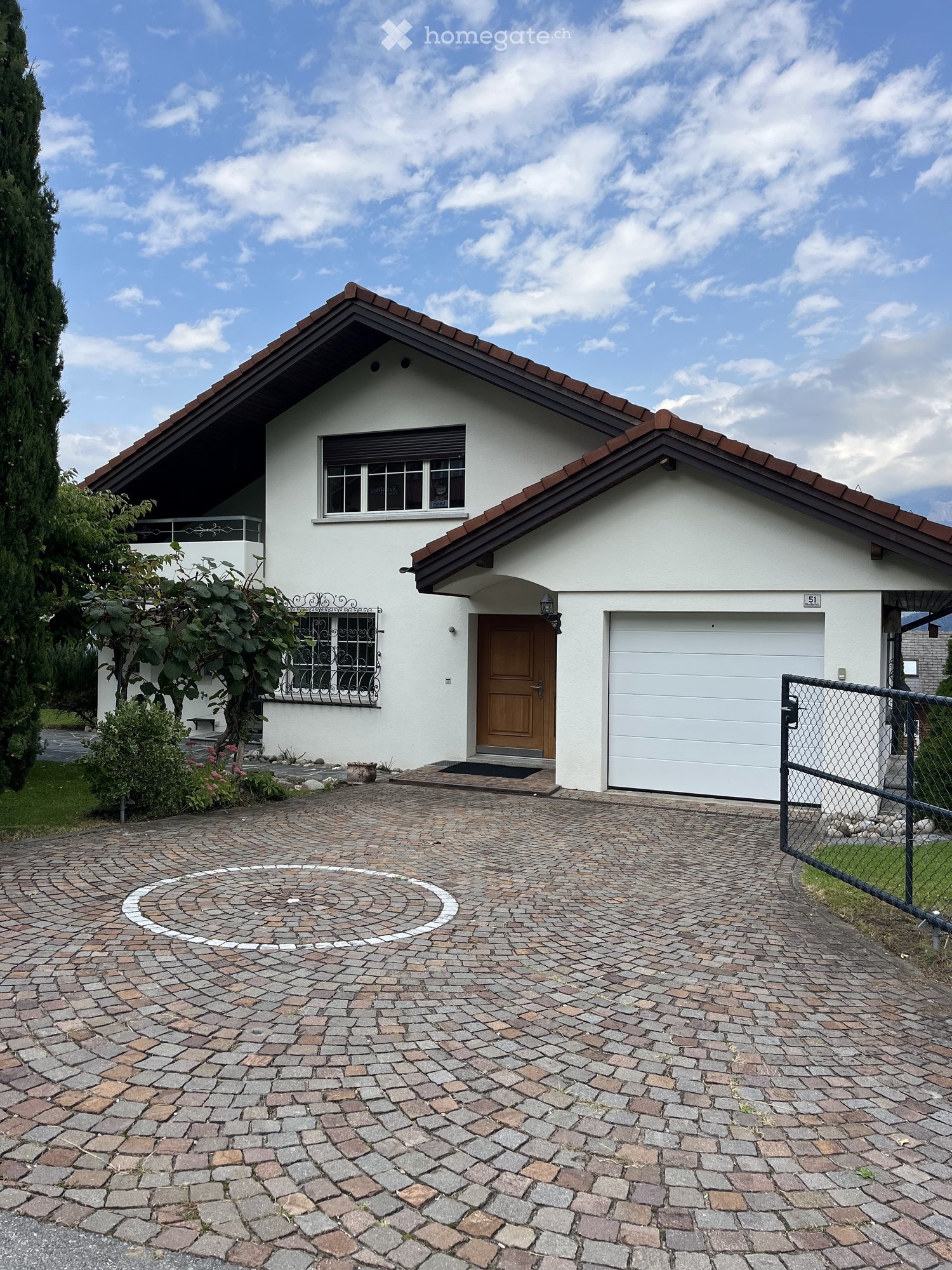 2-story white house with a brown roof, paved driveway, attached garage, garden, fence
