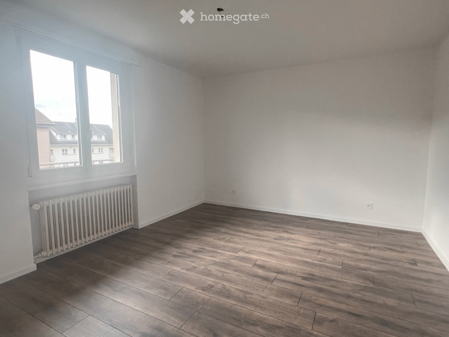 Empty room, white walls, wooden floor, window, white radiator