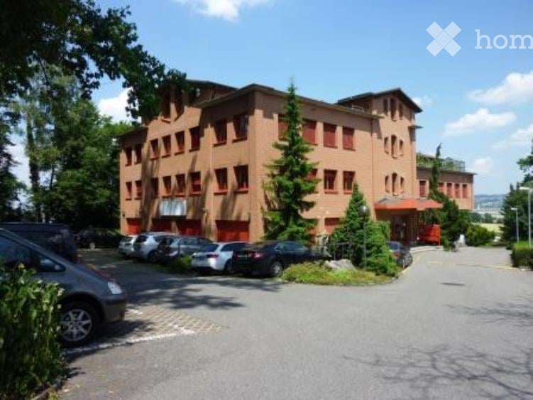2 story brown brick building with many windows, parking lot