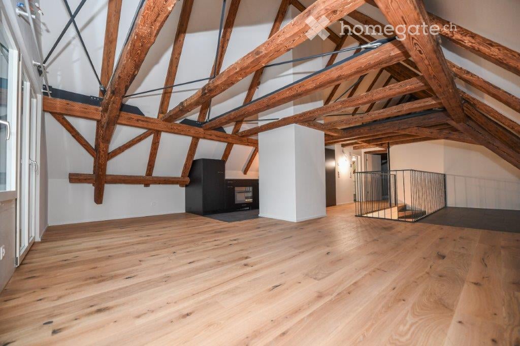 wooden beams, hardwood floor, white walls, balcony, small black cabinet, metal railing