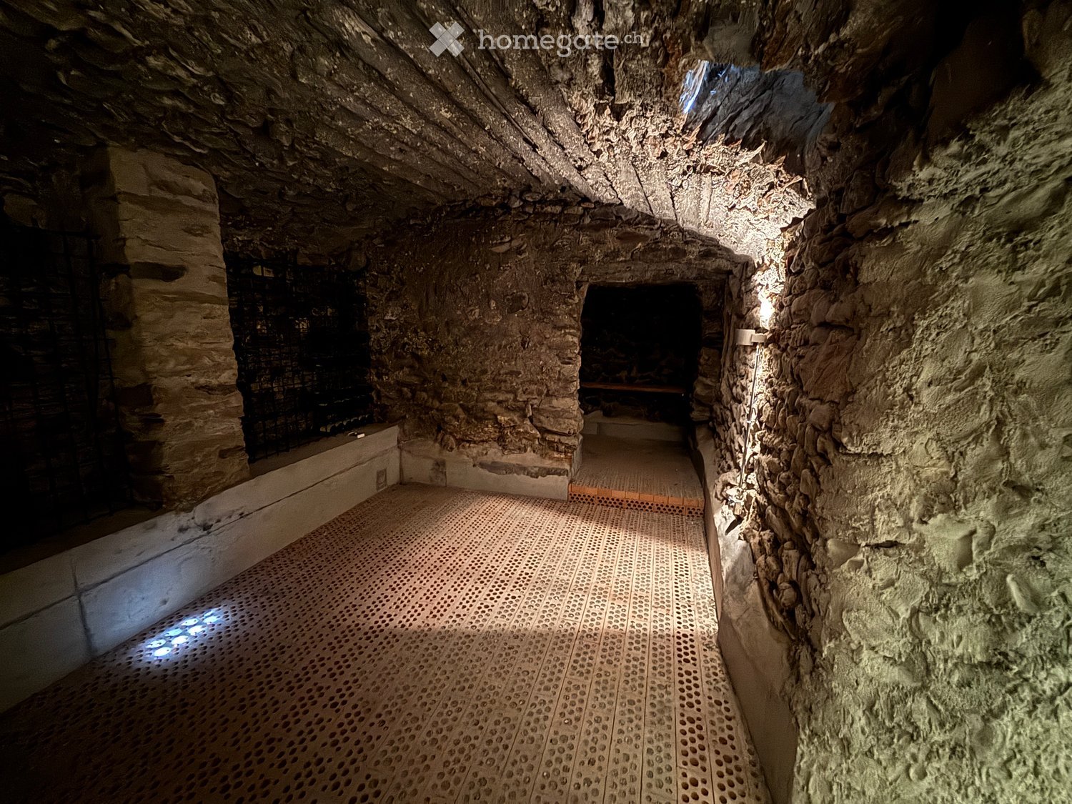 Stone tunnel with a wooden floor, natural lighting, a door, and stone walls