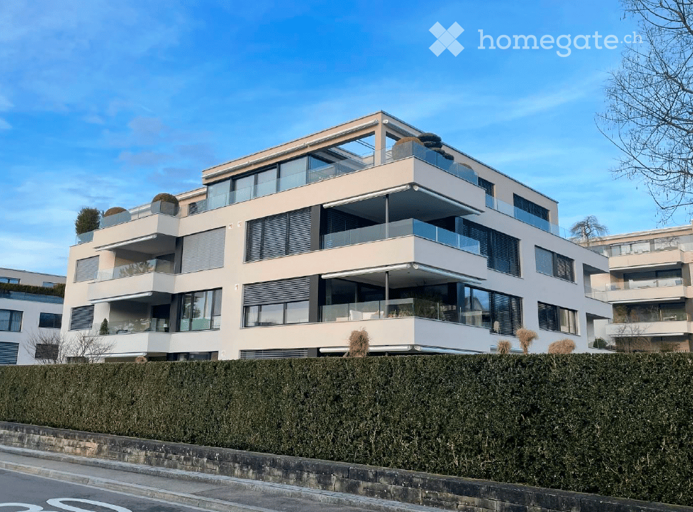 Modern white building, 4 stories, glass balconies, large windows, green rooftop garden