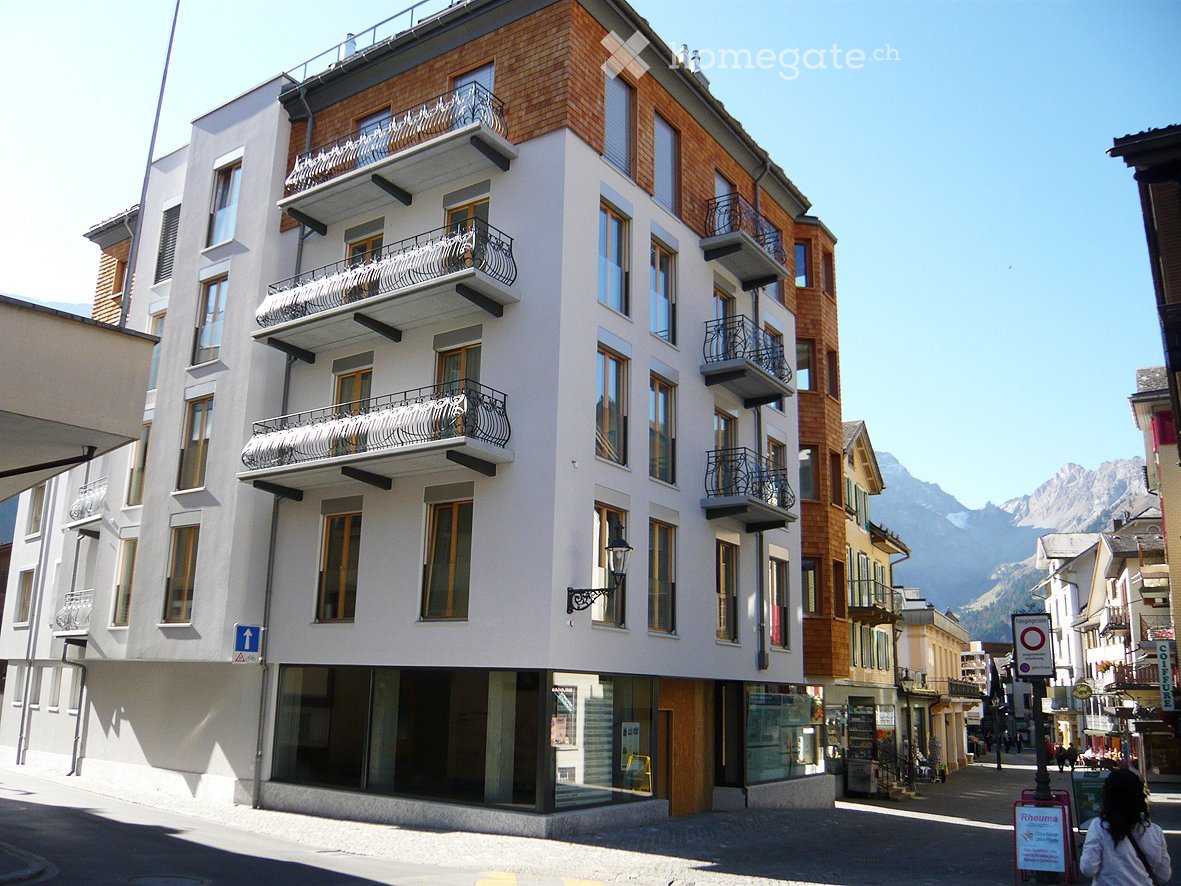 5 story white and brown building, multiple balconies, ground floor shop windows