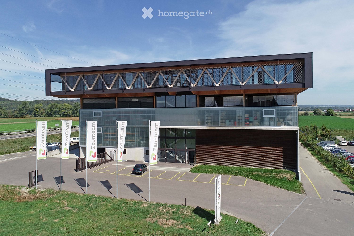 modern building with glass facade, wooden elements, ground floor entrance, car parked in front, parking lot
