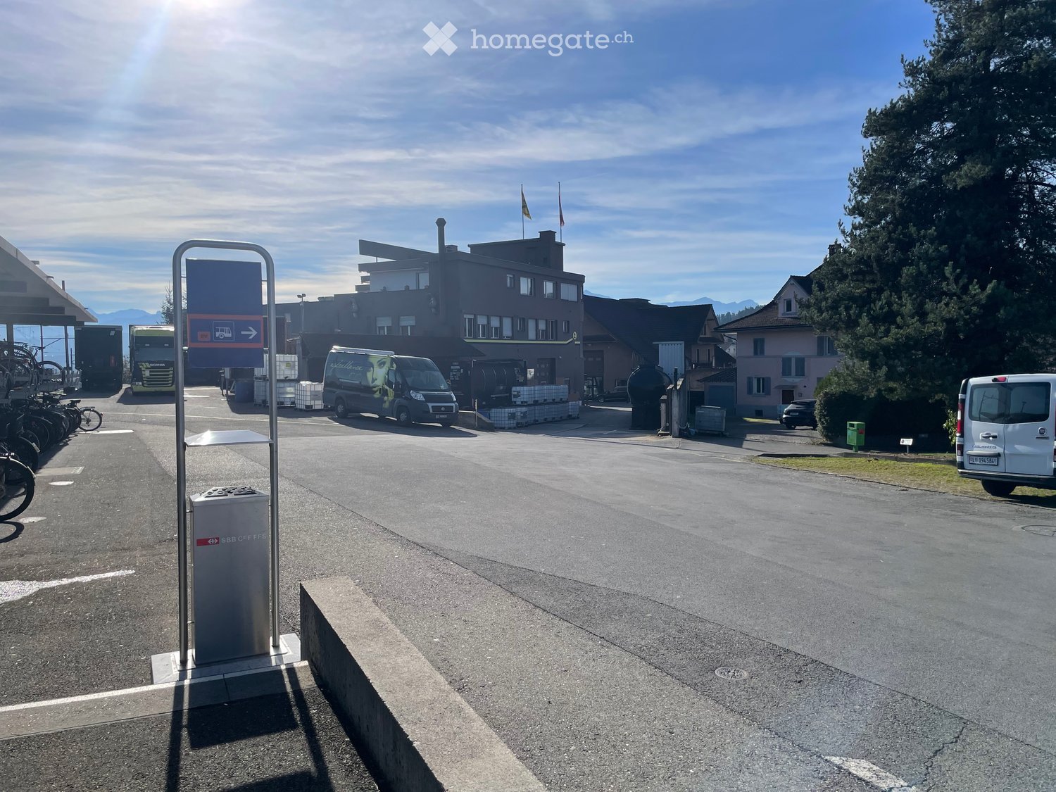 Parking area with parked vans and trucks, road, buildings, streetlight