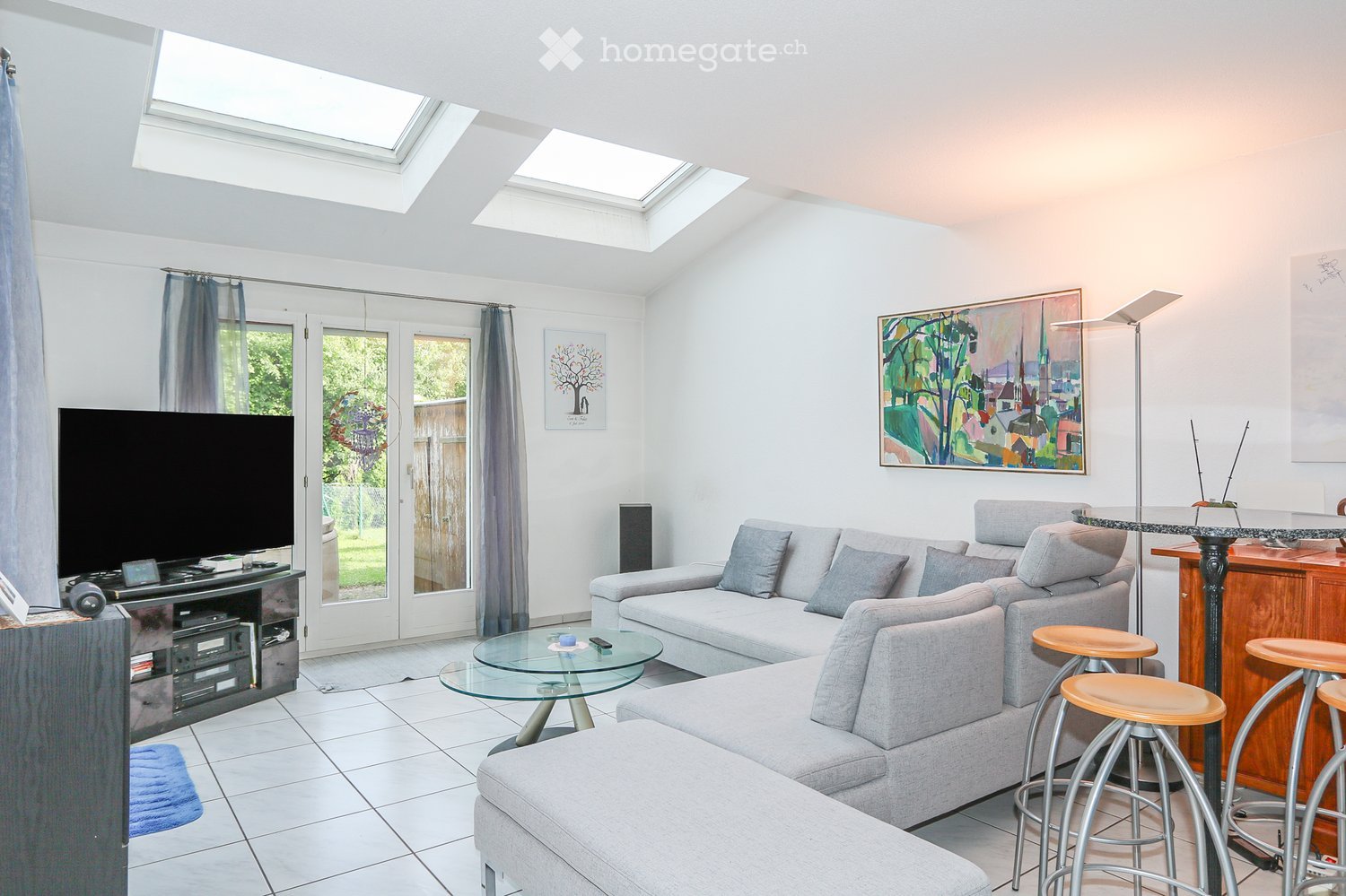 modern living room with two sofa, flatscreen television, coffee table, floor to ceiling windows, round table, grey walls, tiled floor, artwork