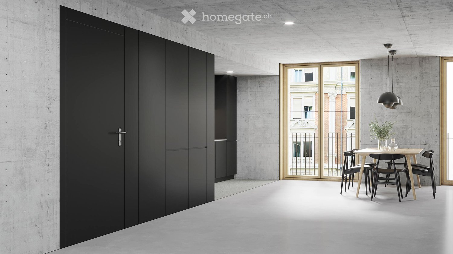 Large open-plan living area with concrete walls and ceiling, black built-in cabinets, wooden dining table and chairs, and a balcony with a view of the surrounding buildings.